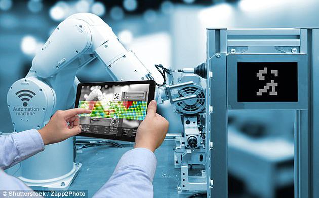 图为工作人员正手持一台增强现实显示屏，无线操控一家智能工厂中的机器臂。