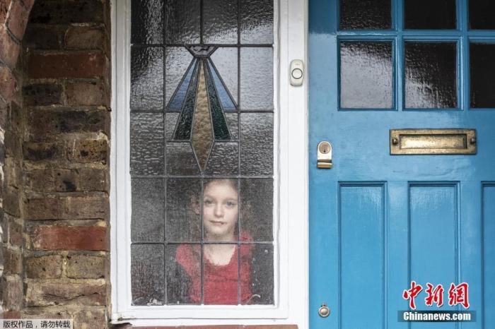 资料图：英国布莱顿，英国摄影师JJ Waller在2020年3月19日至5月21日期间，拍摄了超过100组个人及家庭在窗户、门以及阳台玻璃之后的肖像照。